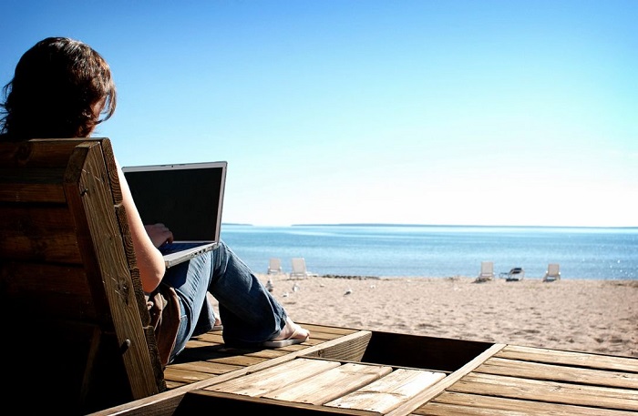woman using laptop on the beach